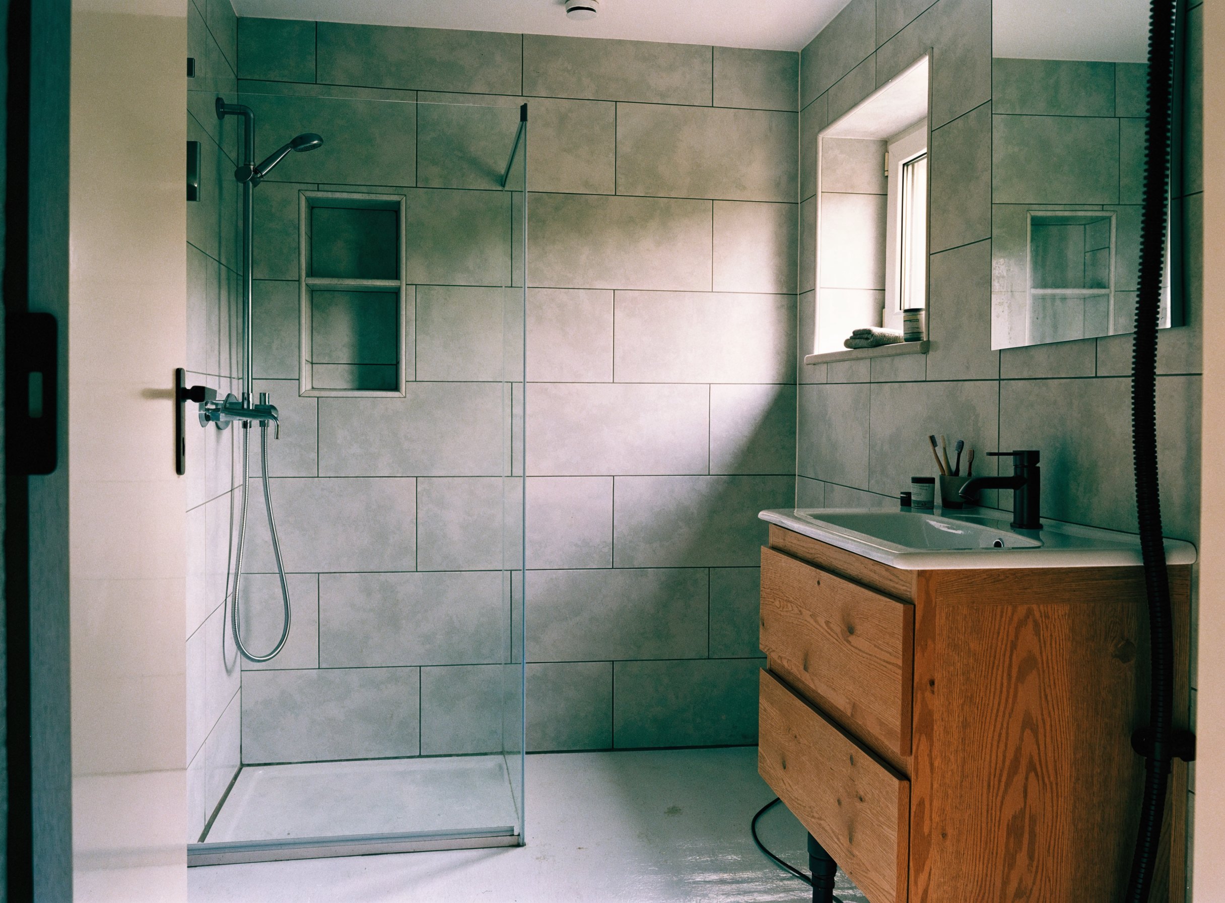 Frisch saniertes Bad mit großformatigen Wandfliesen und begehbarer Dusche
